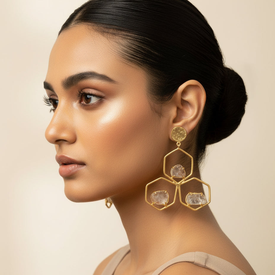 Woman wearing gold earrings with a beige background