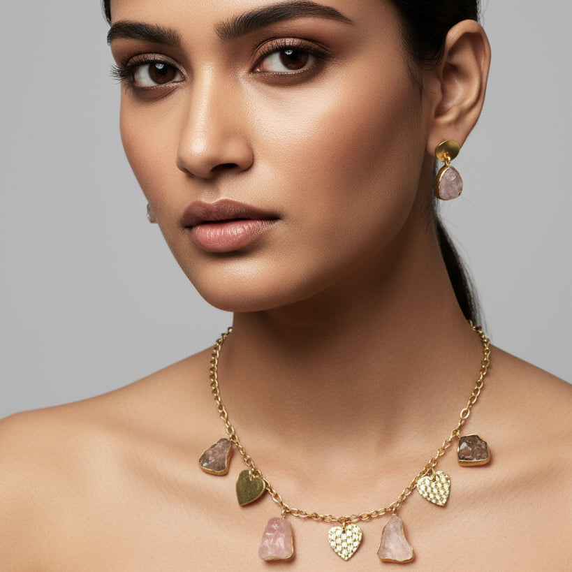 A gold-plated brass necklace with heart-shaped pendants and matching earrings on a dark background.