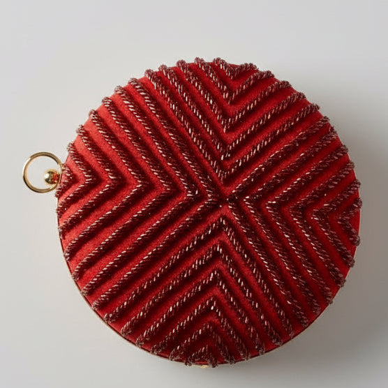 Red textured round pouch on a dark fabric background