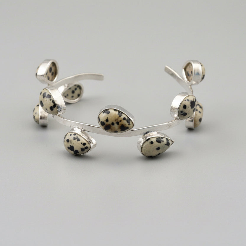 Silver bracelet with dalmatian jasper stones on a light gray background