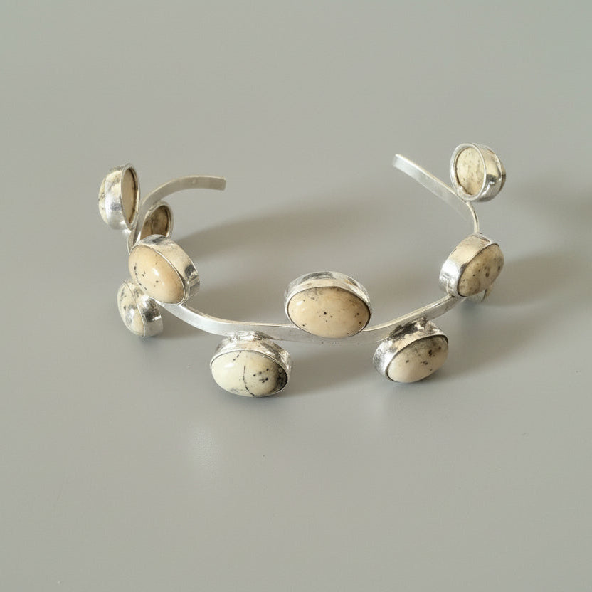 Silver bracelet with beige stones on a gray background