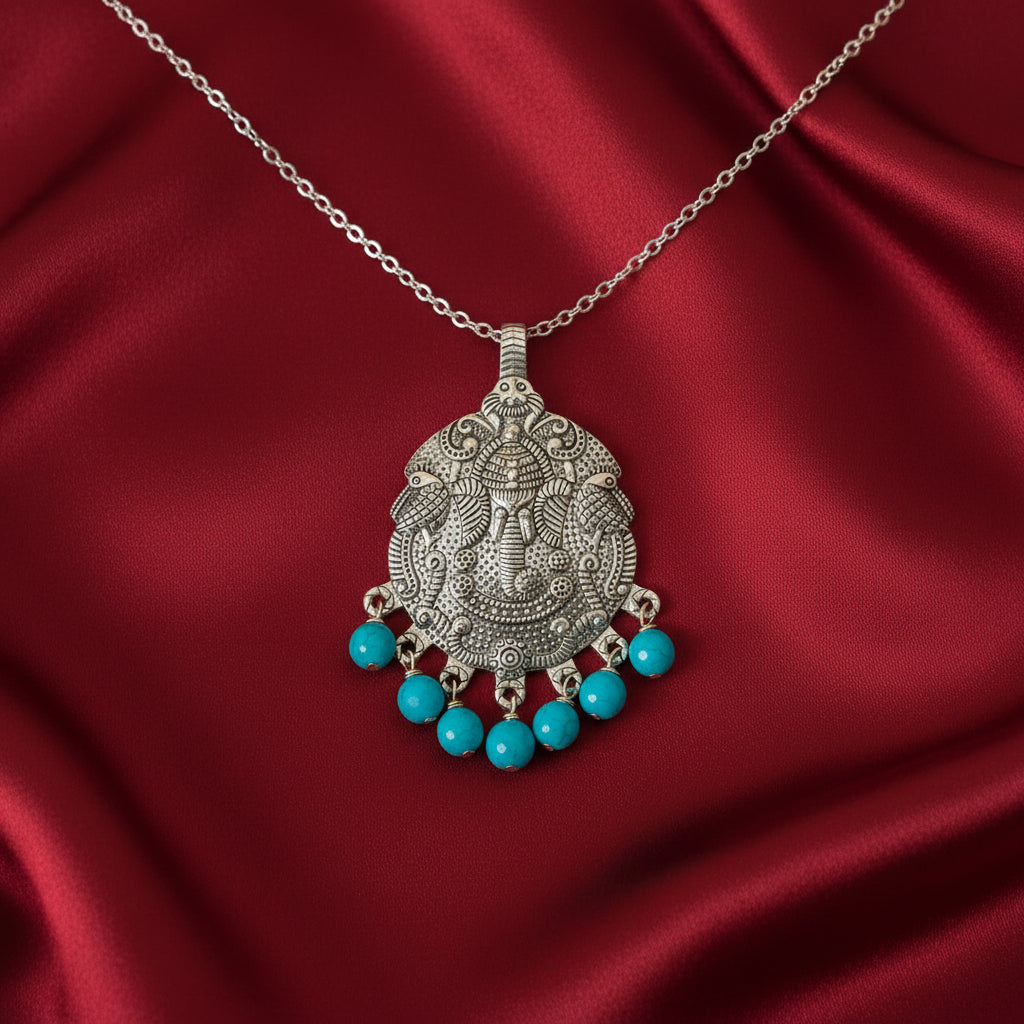 Silver pendant with turquoise beads on a red satin background