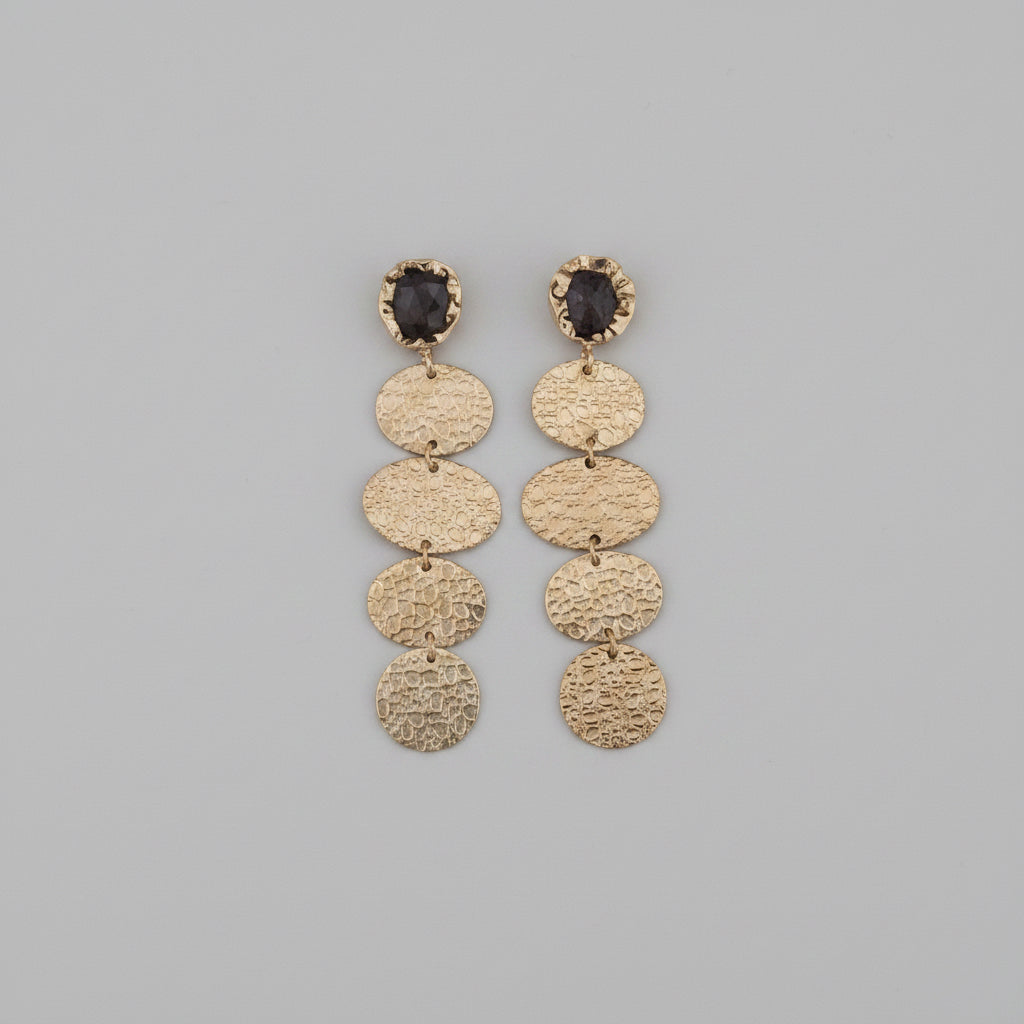 Pair of silver earrings with circular designs on a black background