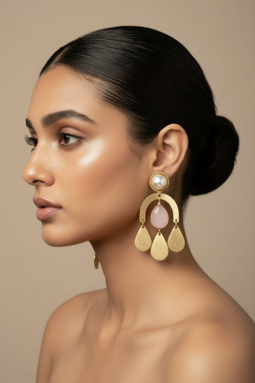 Gold earrings with pearl and pink stone drops on a black background