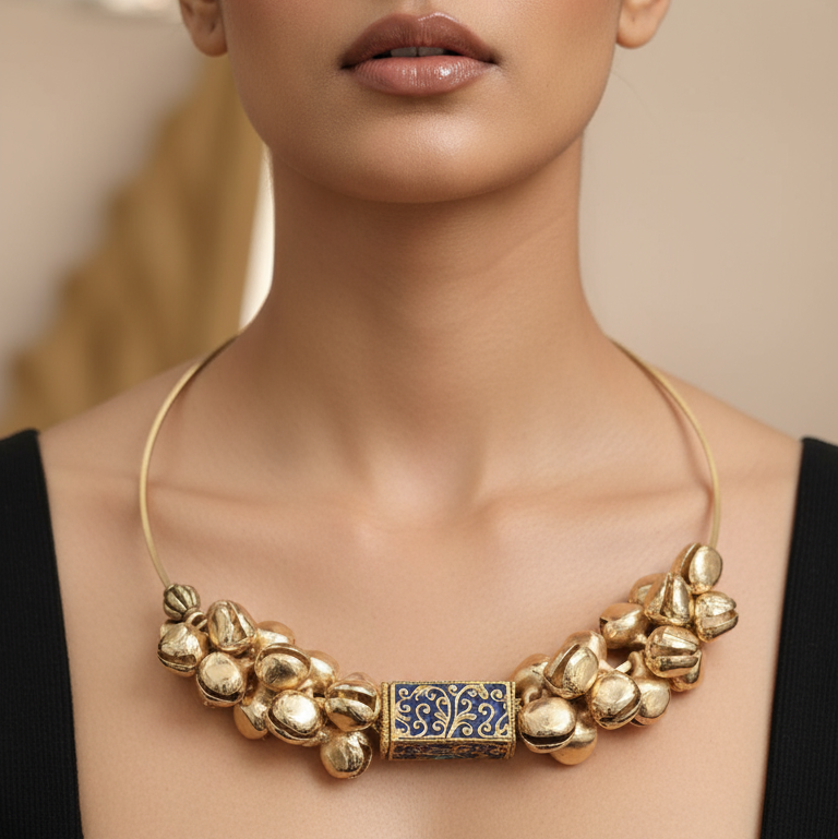 Woman wearing a gold necklace with a prominent clasp against a neutral background