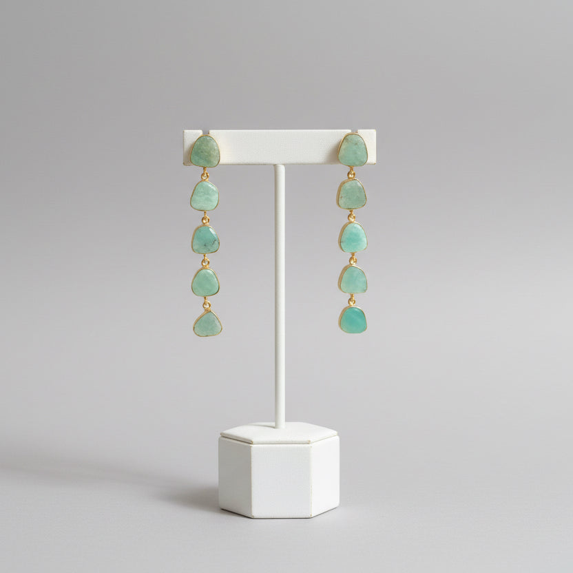 Pair of green teardrop earrings on a dark fabric background