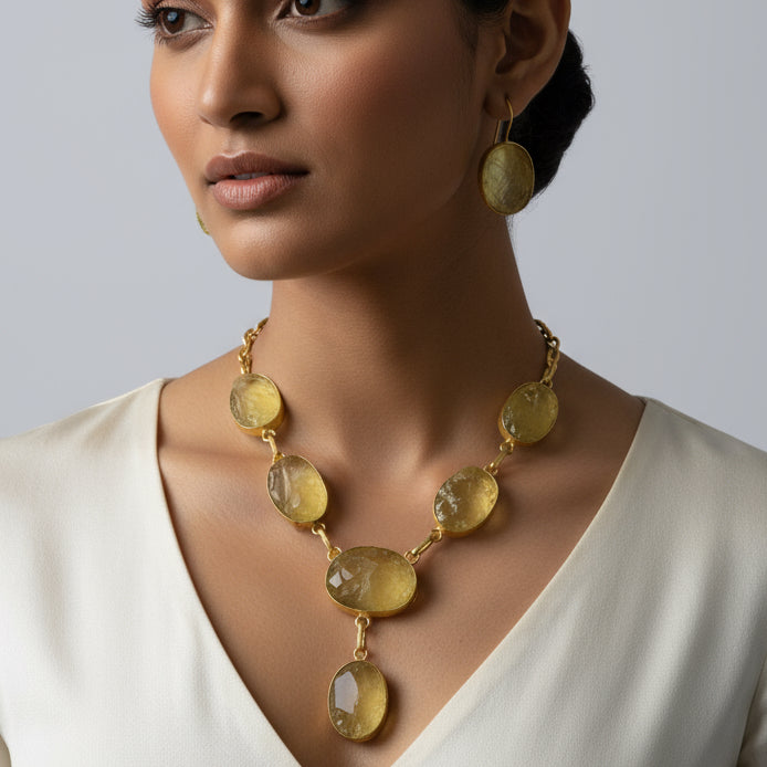A lemon yellow necklace with uncut stones displayed on a black mannequin bust, accompanied by matching earrings.