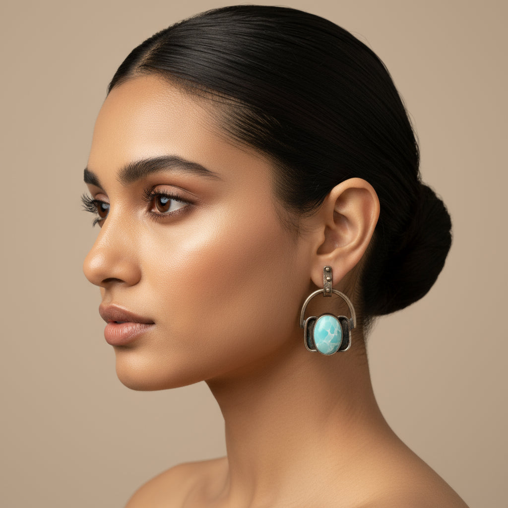 A pair of handcrafted turquoise earrings with a metallic and glass bead design, displayed against a black background.