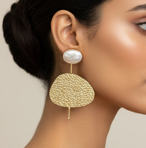 Gold earrings with textured design on a black card
