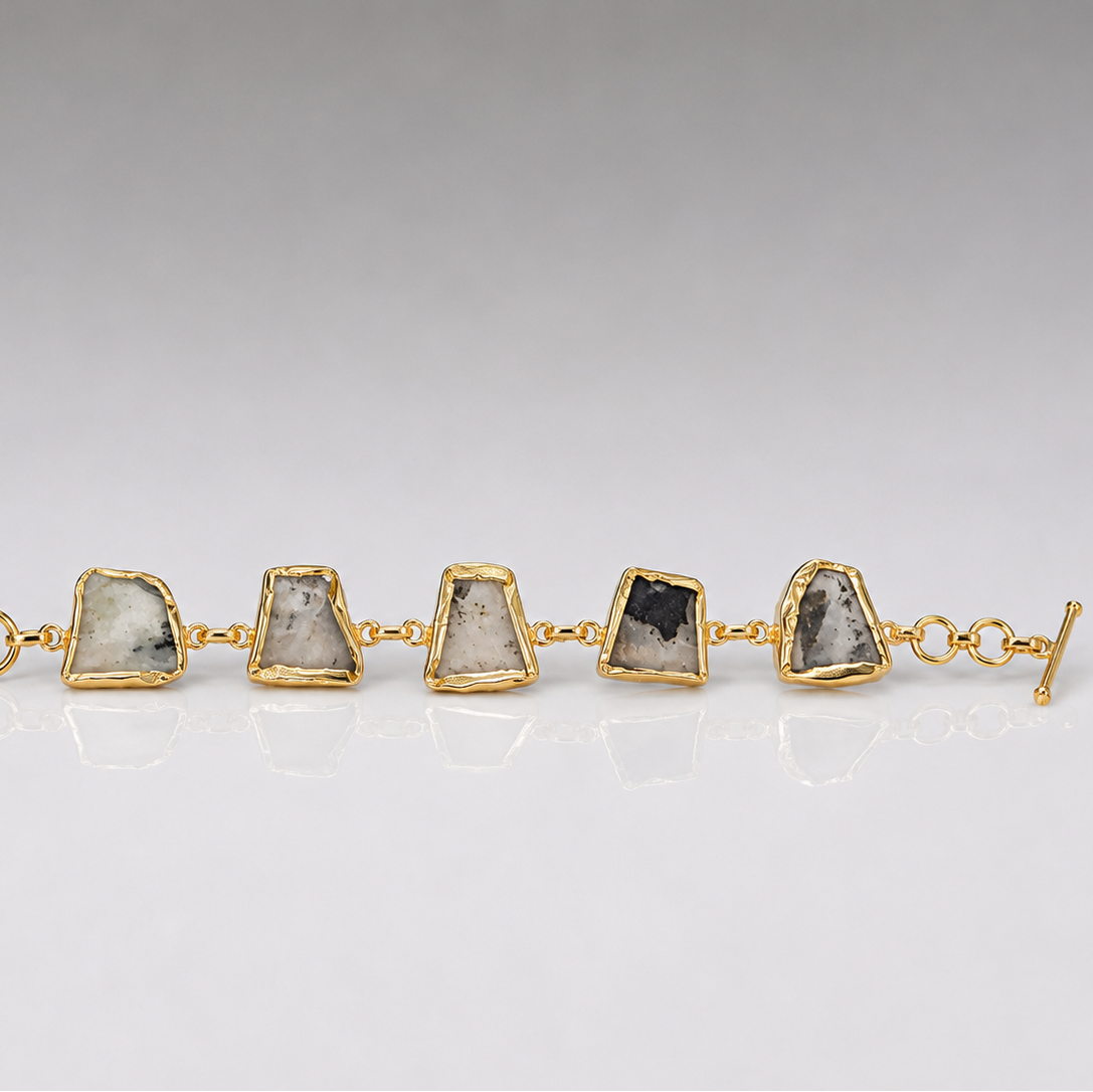 Gold bracelet with stone accents on a gray background