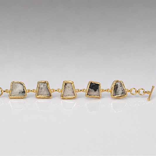 Gold bracelet with stone accents on a gray background