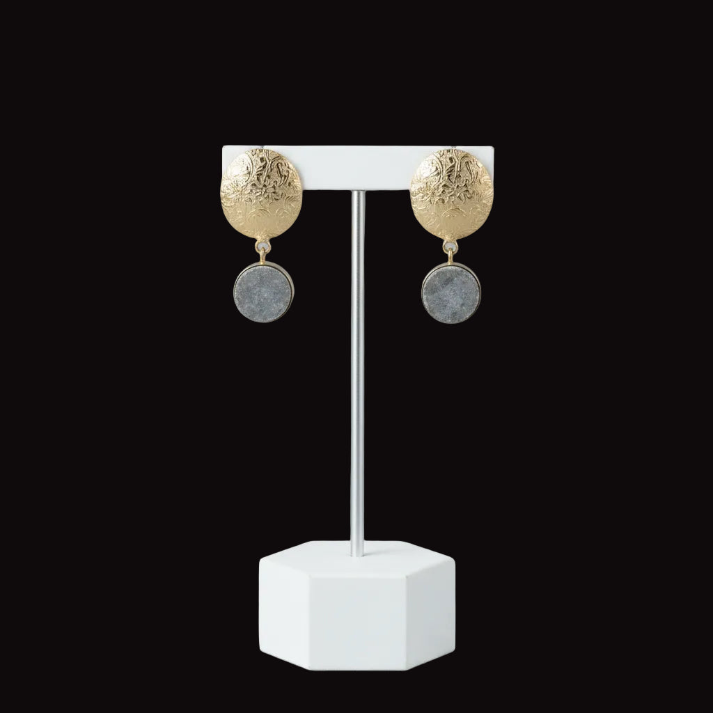 A pair of vintage gold-toned dangle earrings with textured oval top plates and round gray stone or enamel drop pendants, displayed on a solid black background.