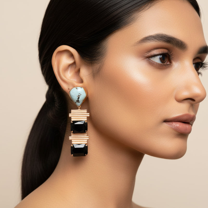 Pair of earrings with brown gemstones and gold accents on a blue textured background