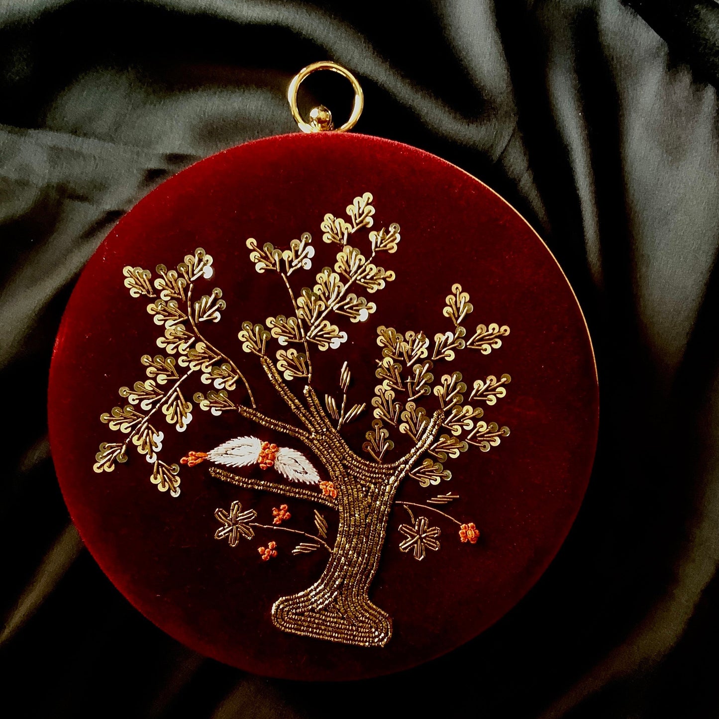 Decorative pendant with gold tree design on a red background
