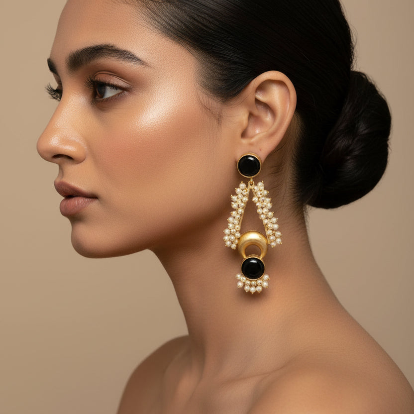 Pair of earrings on a black card against a gray fabric background