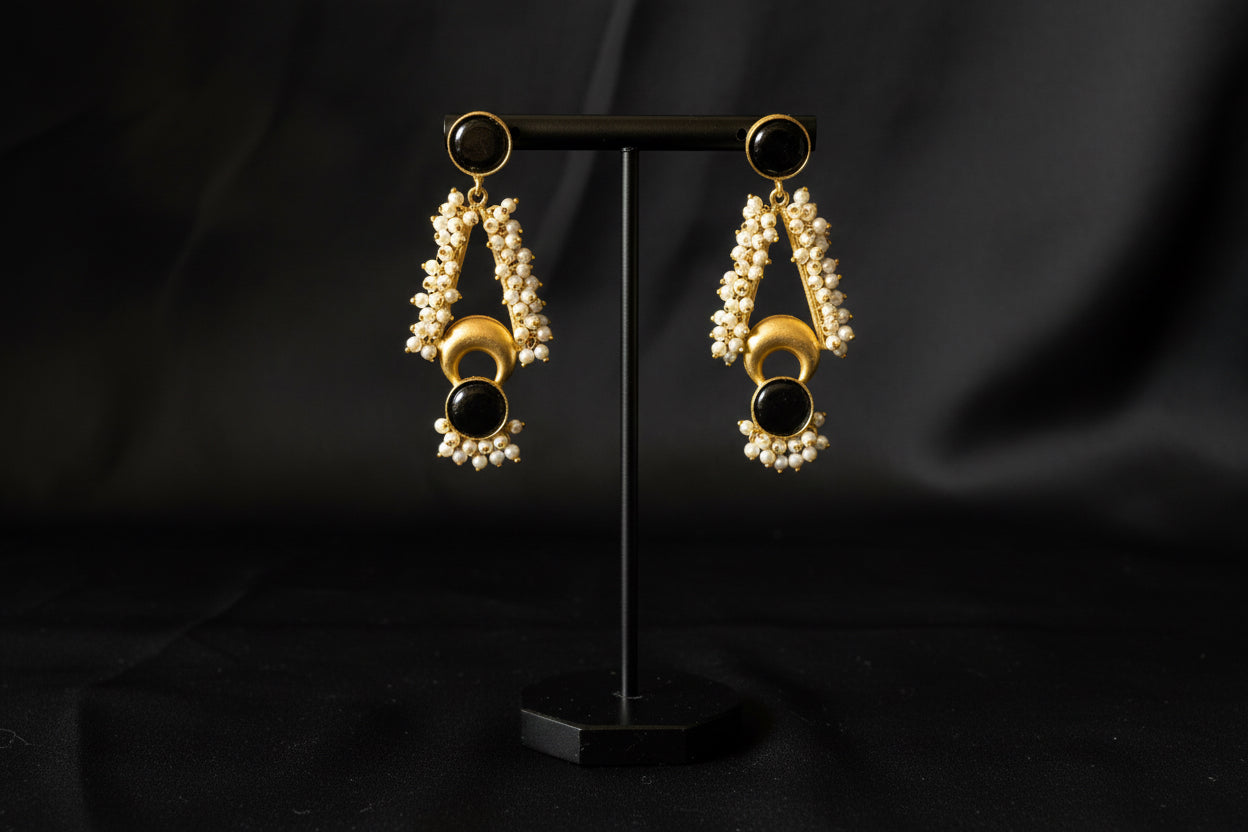 Pair of earrings on a black card against a gray fabric background