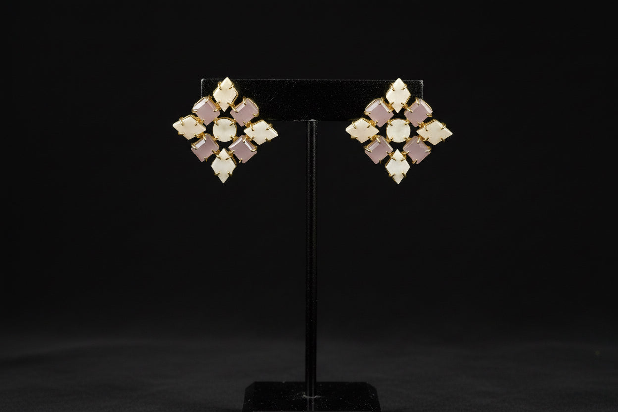 Pair of diamond-shaped earrings on a black stand against a black background