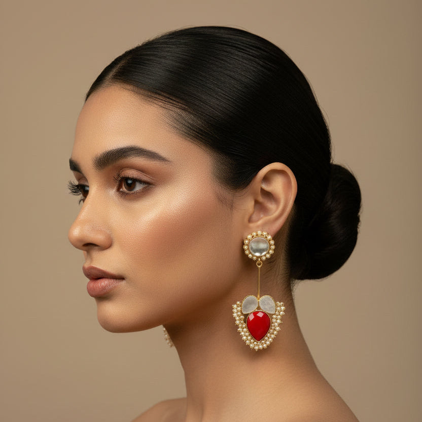 Woman wearing a large, ornate earring with a red gemstone on a beige background