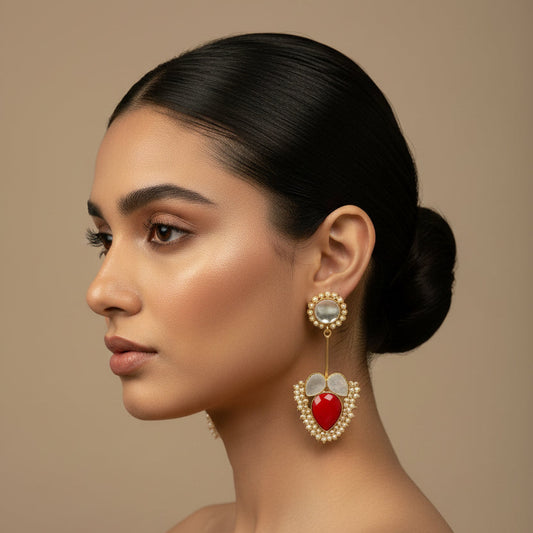 Woman wearing a large, ornate earring with a red gemstone on a beige background