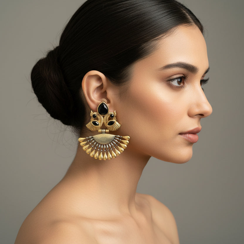 Pair of gold and black earrings on a gray fabric background