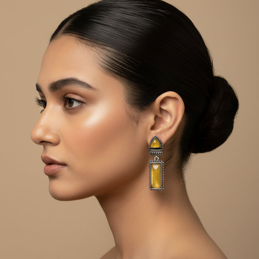 Pair of earrings with yellow stones on a dark fabric background