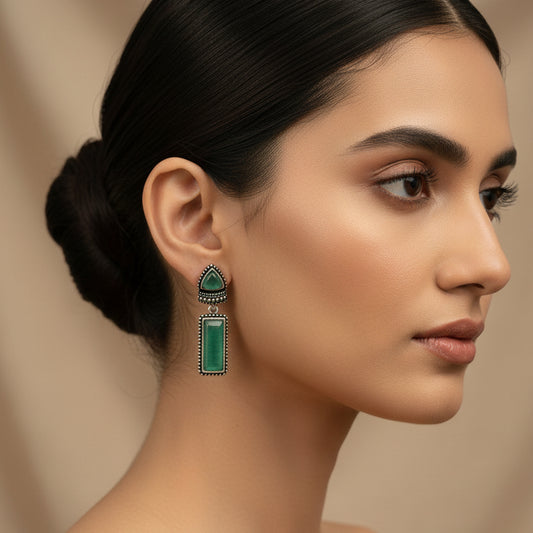 Pair of earrings with green stones on a dark fabric background