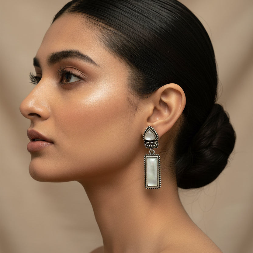 Pair of silver earrings with gemstones on a dark fabric background