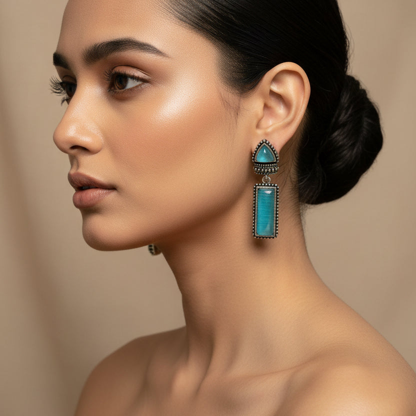 Pair of turquoise earrings on a dark fabric background