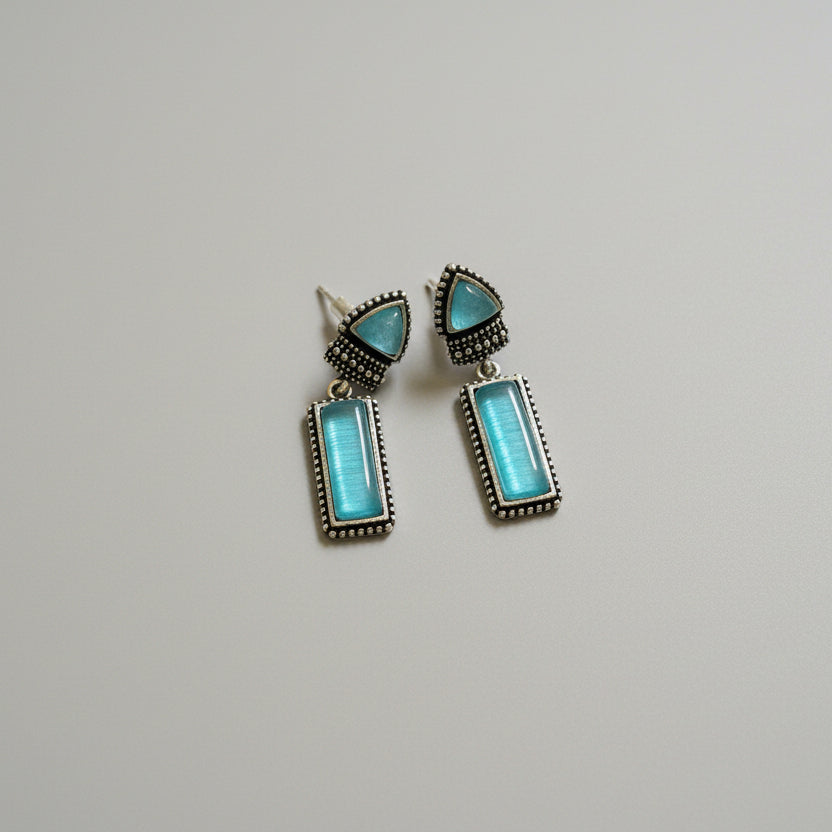 Pair of turquoise earrings on a dark fabric background