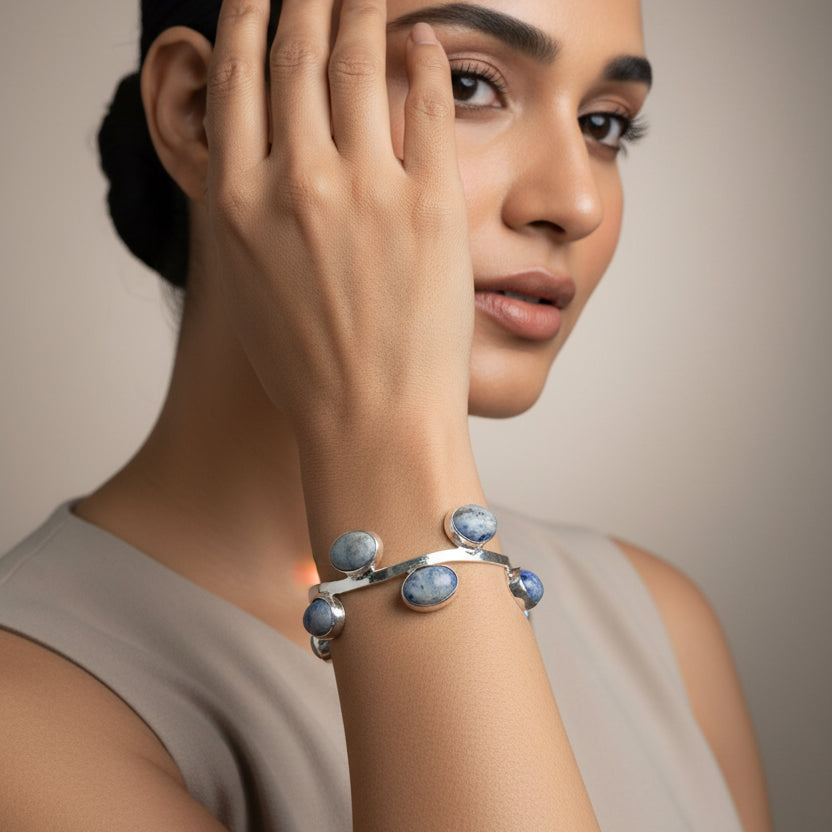 Silver bracelet with blue stones on a wrist against a blurred background