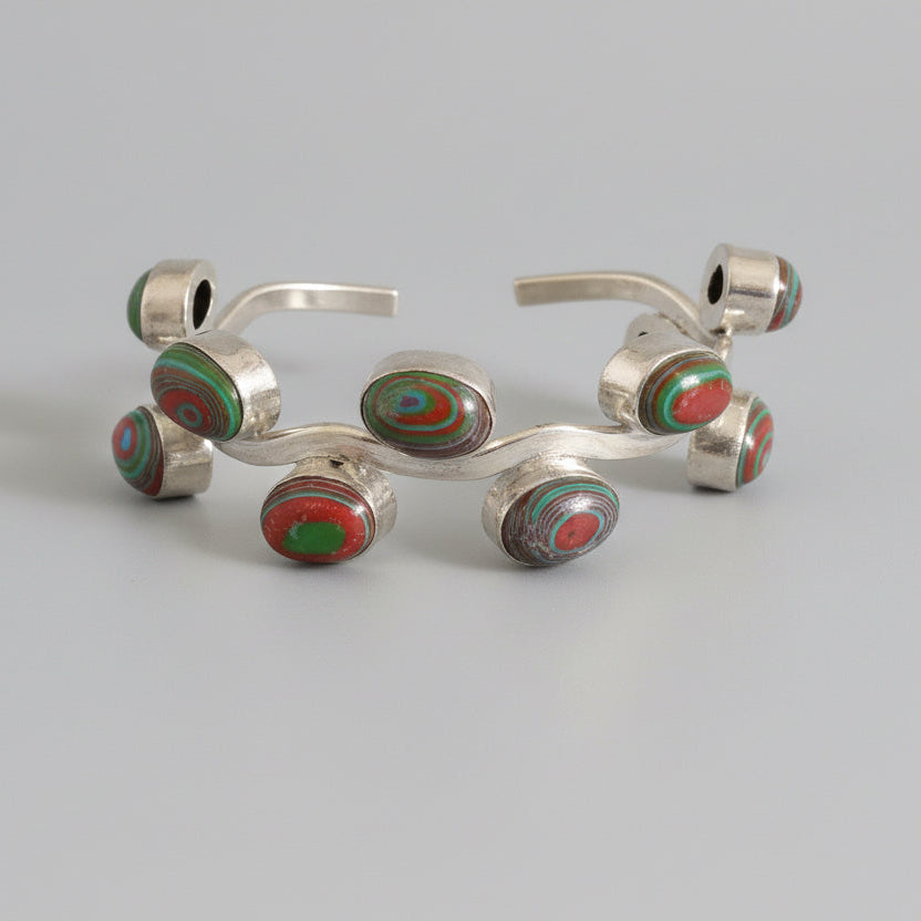 Set of metal earbuds with green and red accents on a dark fabric surface