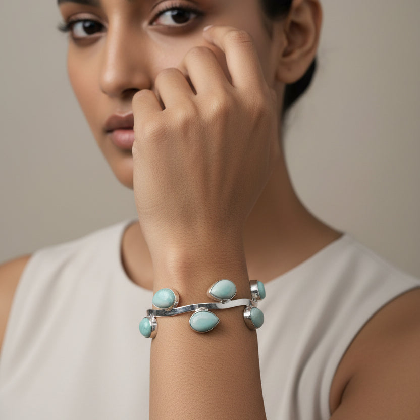 Bracelet with green stones on a wrist against a striped fabric background