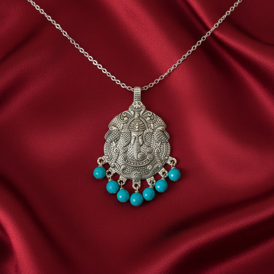 Silver pendant with turquoise beads on a red satin background