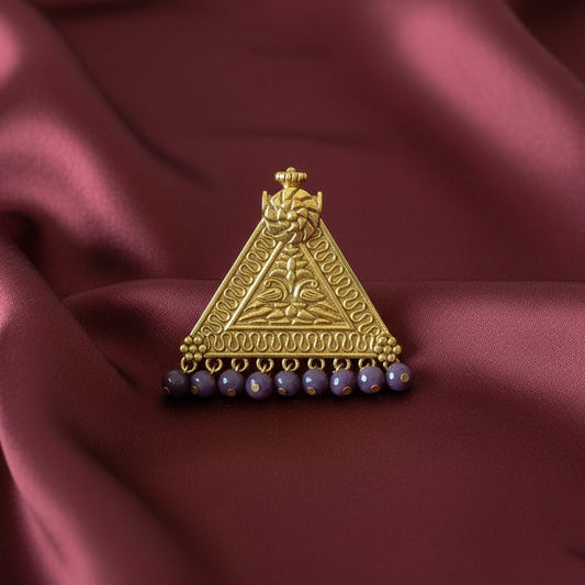 Decorative gold triangle pendant with purple beads on a black fabric background
