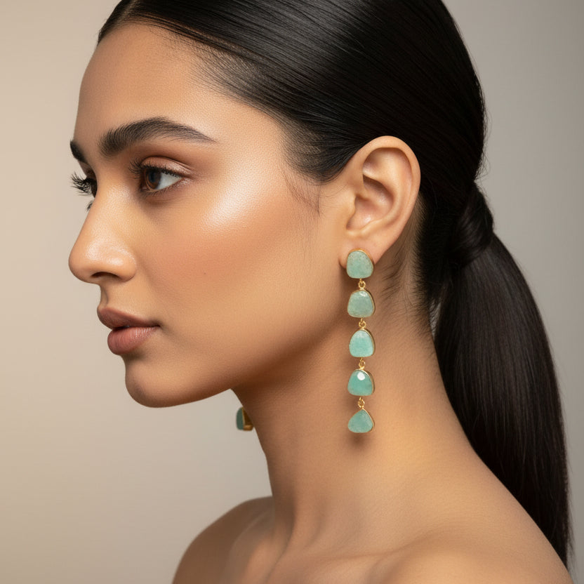 Pair of green teardrop earrings on a dark fabric background