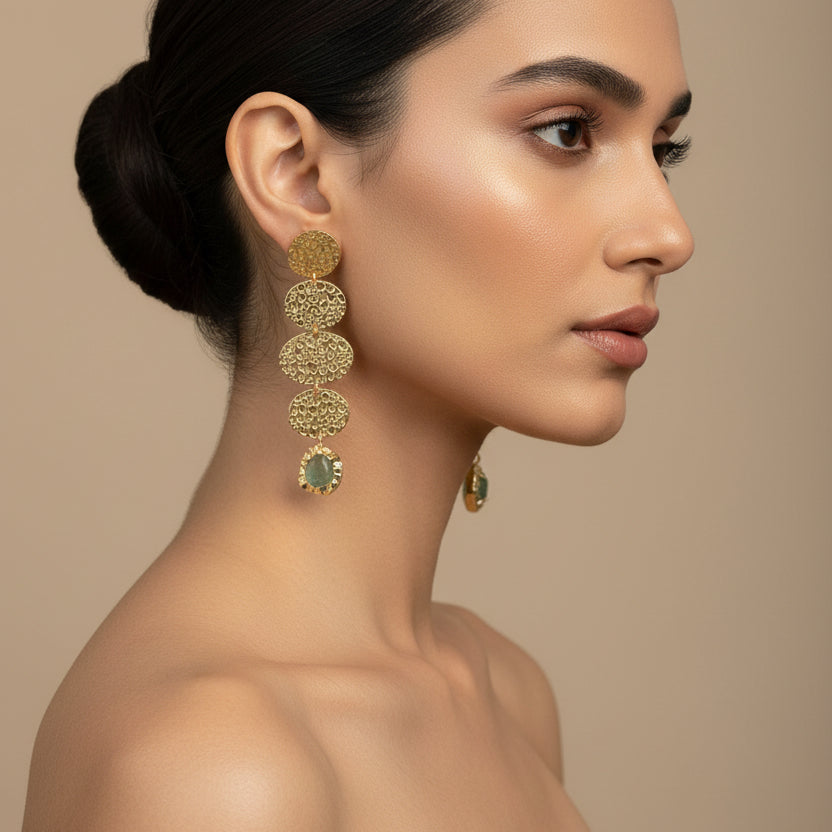 Gold earrings with circular designs on a dark background