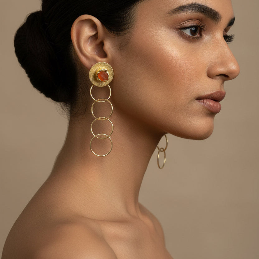 Pair of gold earrings with circular designs on a black background