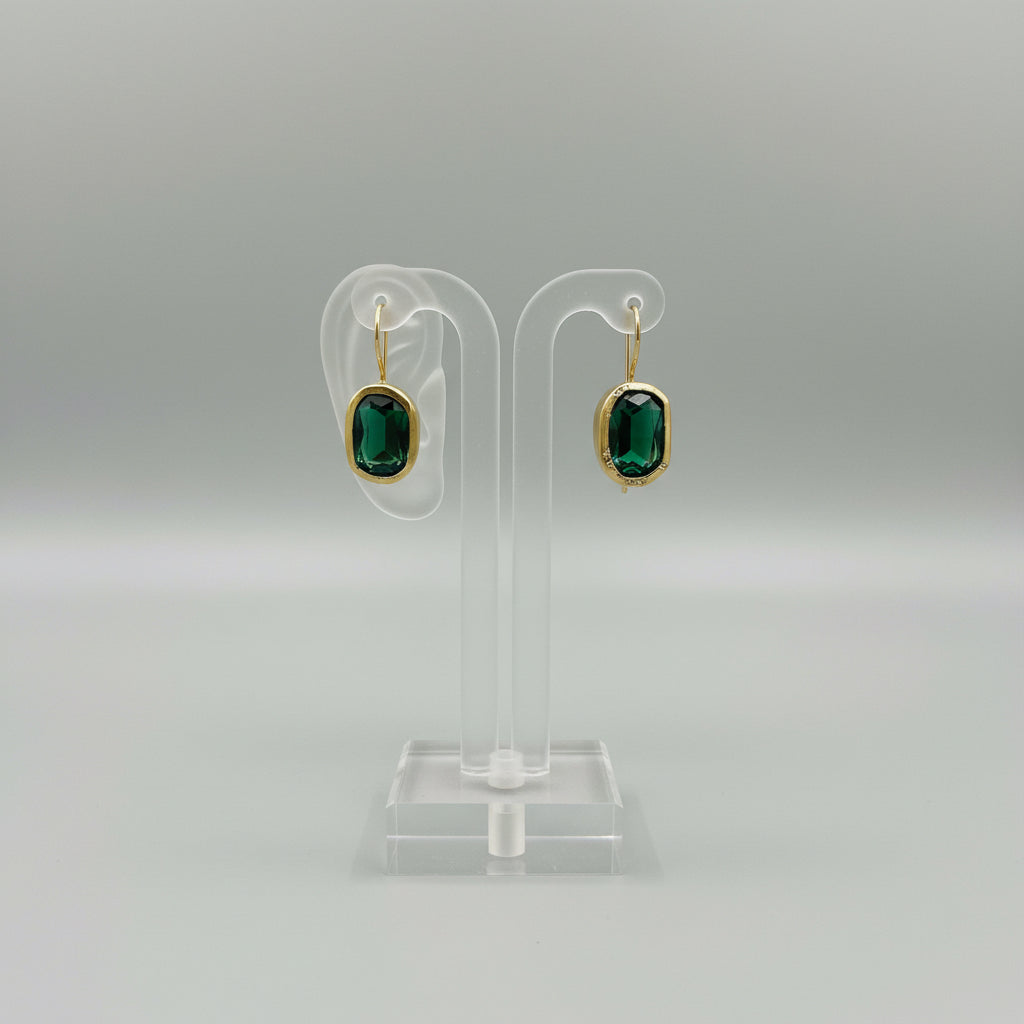 Gold-framed green earrings on a dark surface