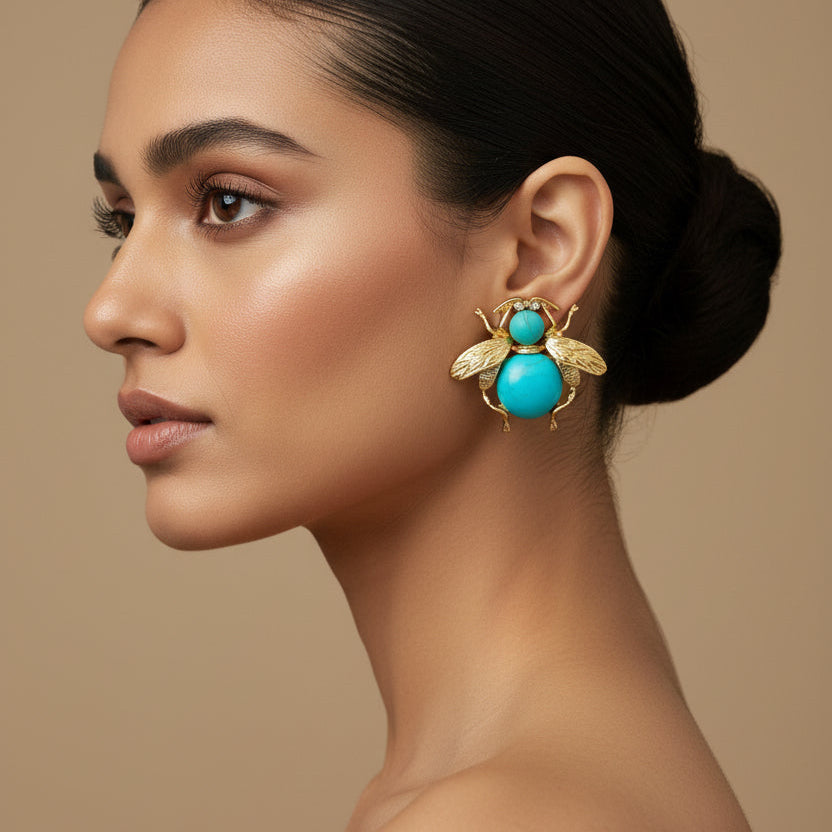 Pair of bee-shaped earrings with turquoise centers on a black card.