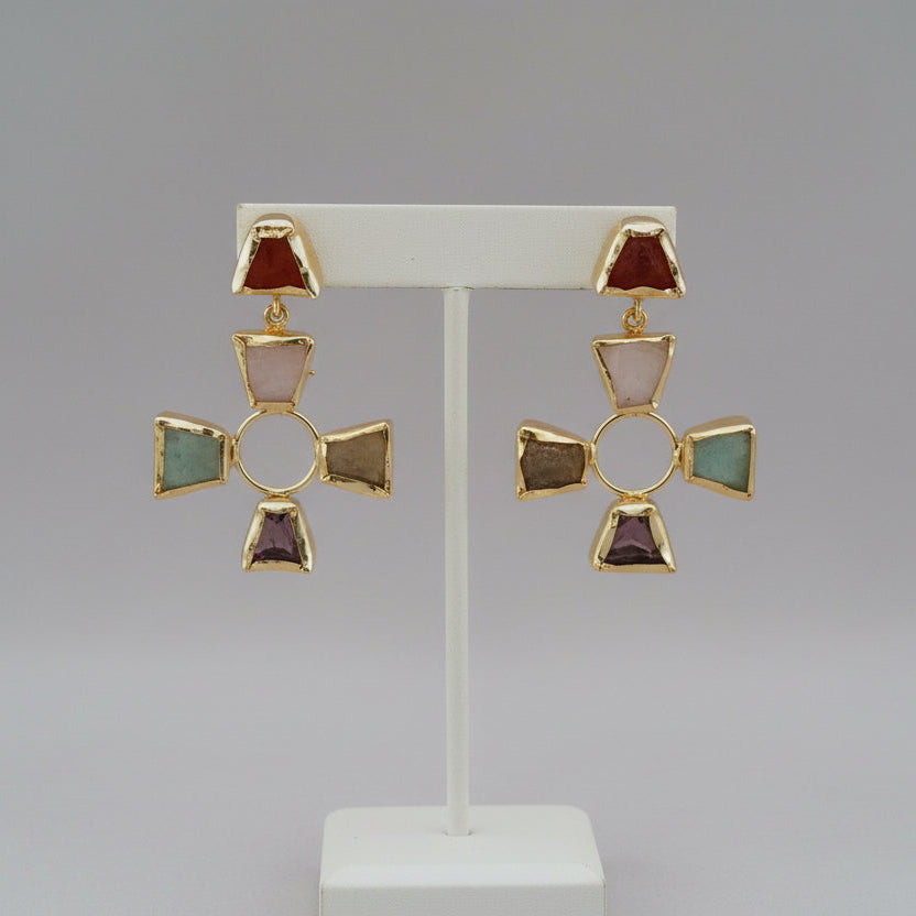 Pair of earrings with cross design on a black surface with a green striped background