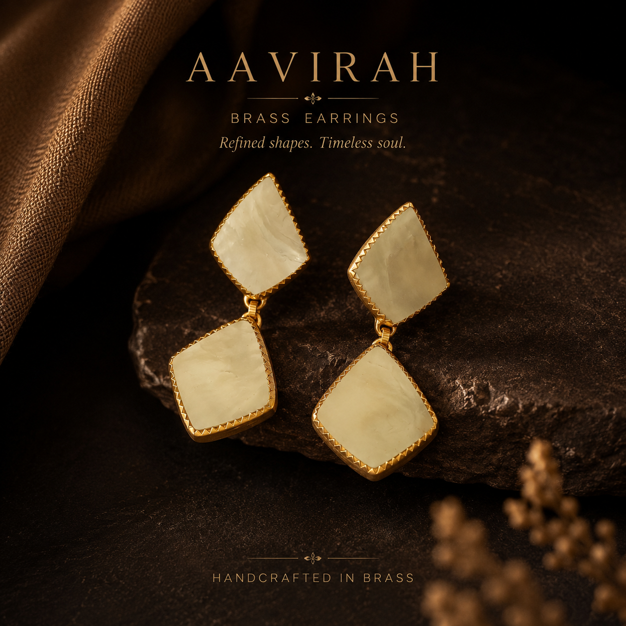 Gold and beige earrings on a dark surface with 'Aavirah' branding.