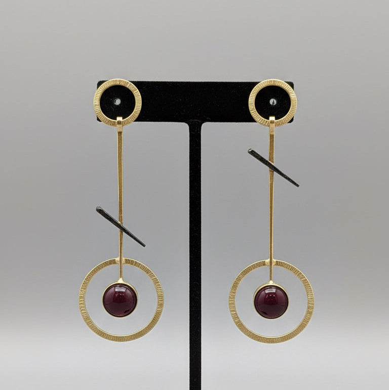 Pair of earrings on a gray card with a textured surface background
