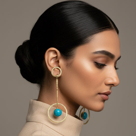 Pair of earrings with turquoise stones on a black card, placed on a textured surface.