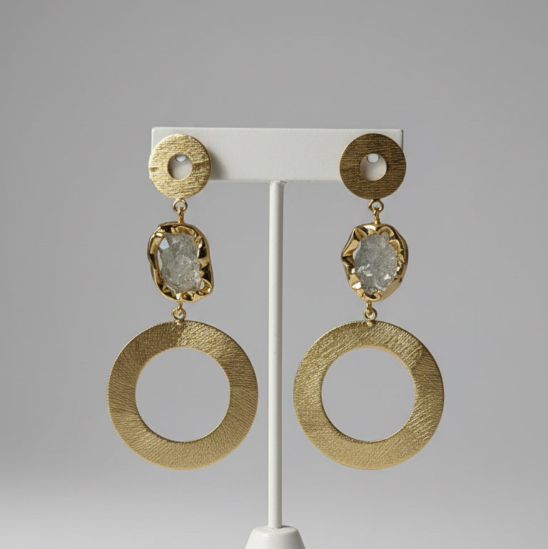 Gold hoop earrings on a black card with a textured brown background