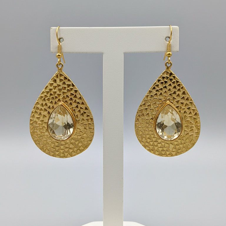 Gold teardrop earrings on a dark gray card against a black background