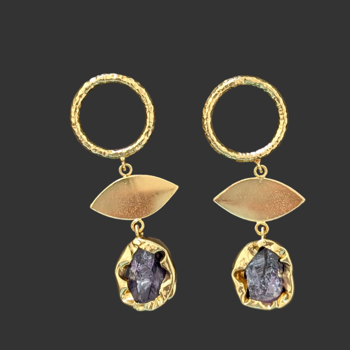 Gold earrings with purple stones on a black card