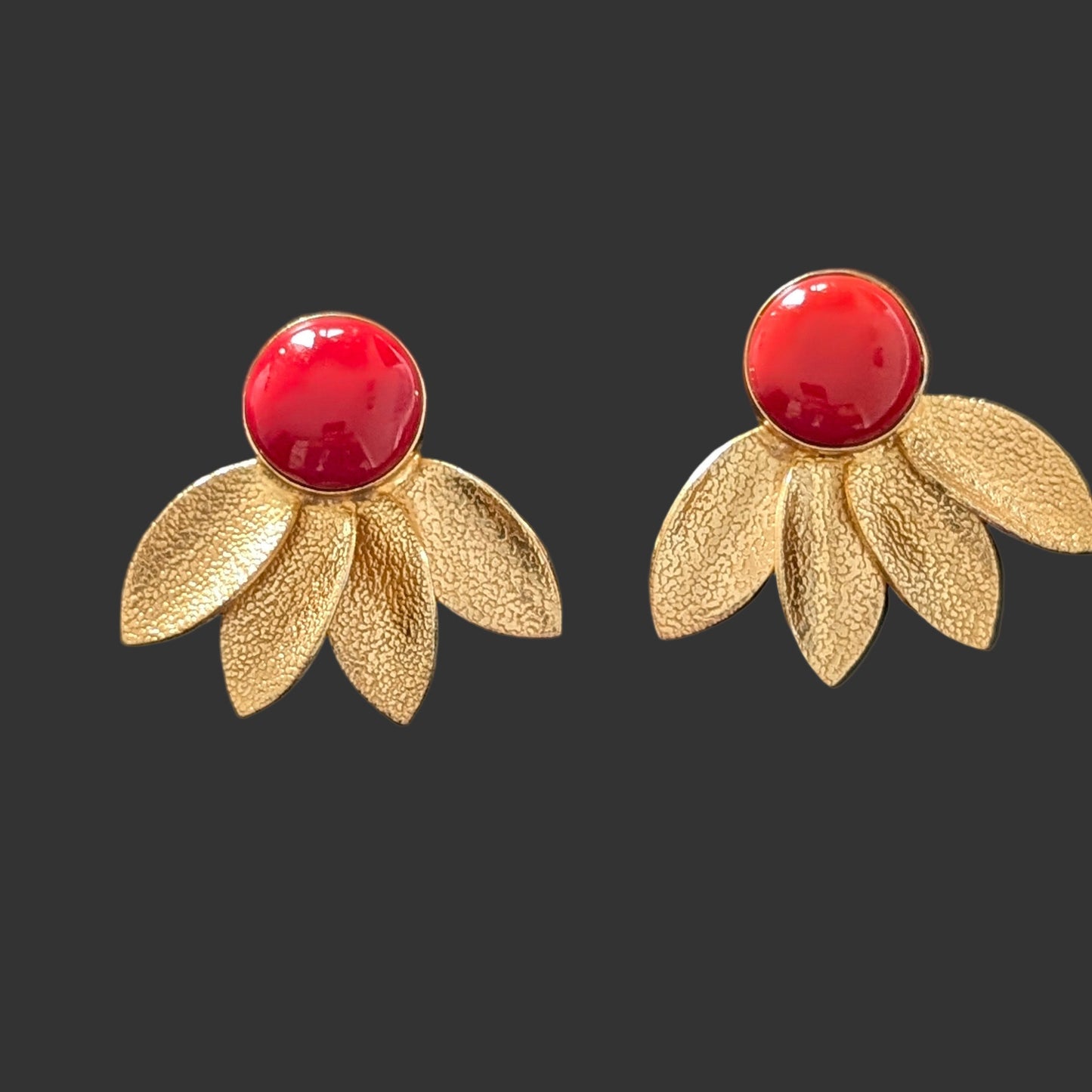 Pair of earrings with red centers and gold floral designs on a black card.