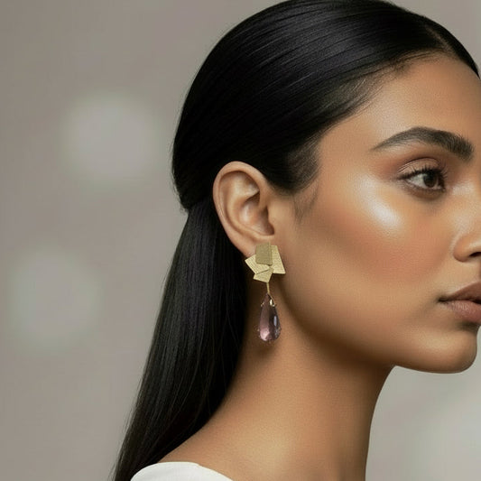 Gold earrings with teardrop-shaped gemstones on a dark background