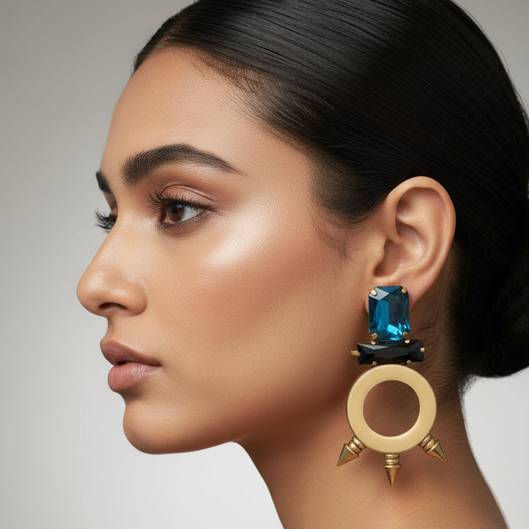 Earrings with blue gemstones and gold circular design on a black background