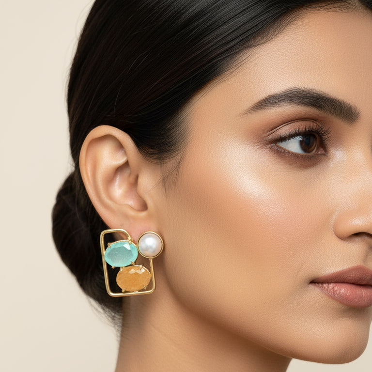Pair of earrings with gold frames, turquoise stones, and pearls on a black card.